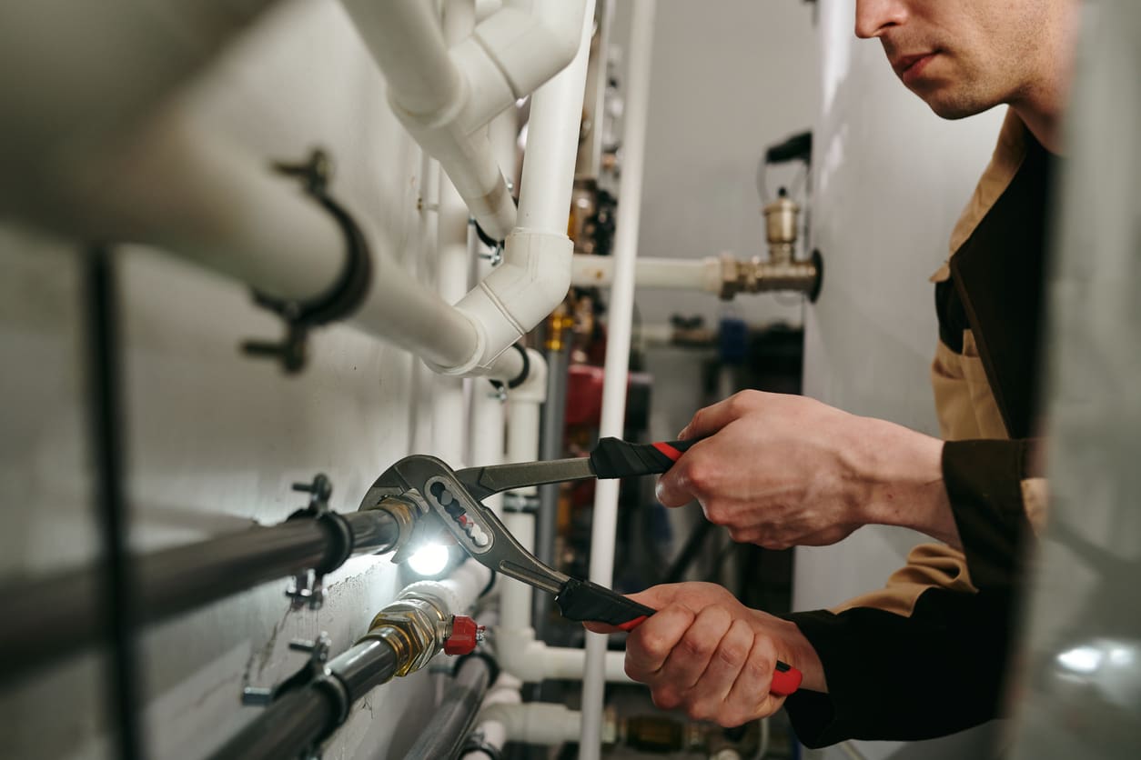 Repairman using a tool to fix parts of pipes during work